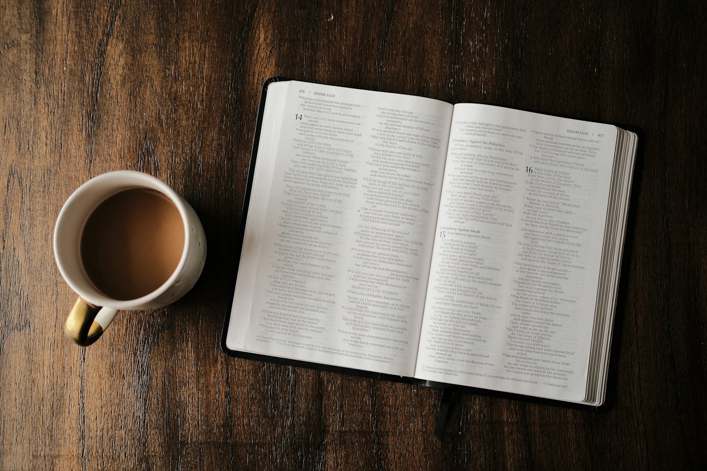 Open boek en mok koffie op een donkere houten tafel.